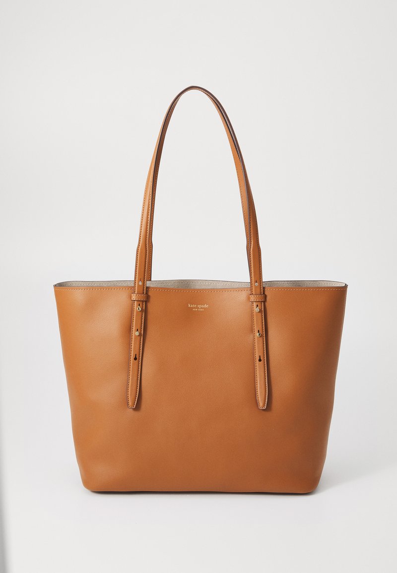 Brown leather tote bag with two long handles, smooth finish, and minimalistic design. Features subtle brand logo on front and neutral interior.