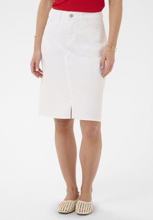 Femme portant une jupe crayon blanche mi-longue fendue sur le devant, un haut rouge, des bracelets dorés, et des chaussures beige tissées à enfiler.