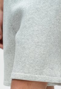 Világosszürke pamut rövidnadrág puha tapintással, hátul zsebbel és a szegélyén finoman hímzett logóval. A szegély fel van hajtva.