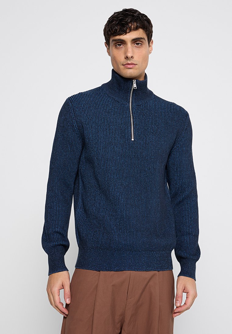 Dunkelblauer Zip-Pullover mit gerippter Struktur, ausgestattet mit einem metallischen Reißverschluss und eng anliegenden Bündchen, aus weichem Strickmaterial gefertigt.