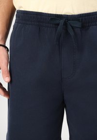 Shorts bleumarin cu talie elastică, având un șnur pentru ajustare și buzunar lateral. Fabricate dintr-un material neted cu o textură subtilă.
