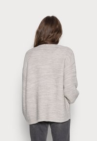 Jasnoszary sweter z dzianiny o luźnym kroju, opadających ramionach i prążkowanych mankietach. Teksturowane poziome wzory na całej powierzchni materiału.