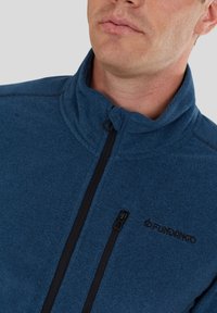 Blue fleece jacket with a high neck, full front zip, and black zipper accents. Features a left chest logo and textured fabric.