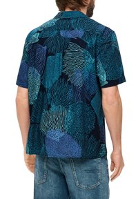 Korte mouwen shirt met een marineblauwe achtergrond en ingewikkelde blauwe en teal koraalachtige patronen. Zachte stof met een ontspannen pasvorm.