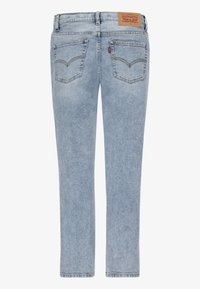 Jeans de mezclilla azul claro con corte recto, que cuentan con dos bolsillos traseros y una etiqueta de marca marrón en la cintura. Textura suave en general.