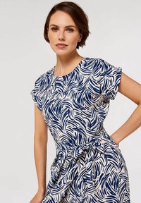 Kurzärmeliges Kleid in Creme mit navyblauen wellenförmigen Mustern, mit Rundhalsausschnitt und einem gebundenen Taillenzug für eine definierte Silhouette.