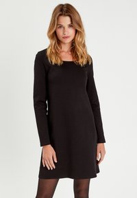 Vestido negro de manga larga con escote cuadrado, hecho de tejido suave, que presenta un corte recto y un dobladillo a la altura de la rodilla.