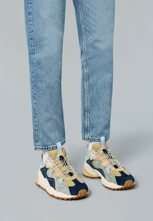 Bunt gefächerte Sneakers aus blauen, beige und grauen Mesh- und Wildledermaterialien. Strukturierte Sohle mit auffälligen Schnürsenkeln und einer Schlaufe.