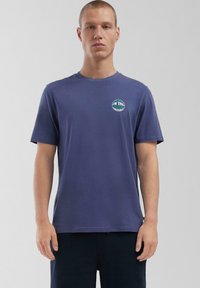 Navyblauwe katoenen T-shirt met korte mouwen, ronde hals en een geprinte cirkelvormige grafiek op de linkerborst. Zachte textuur, casual pasvorm.