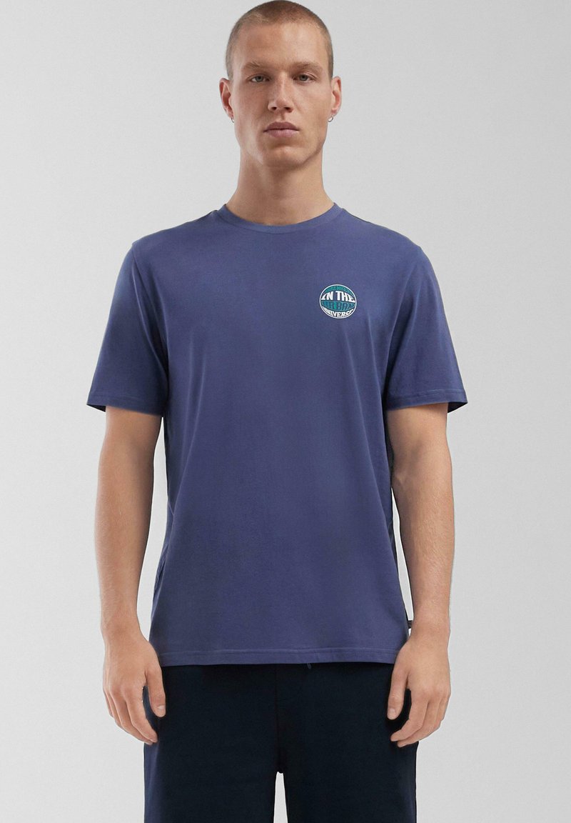Navyblauwe katoenen T-shirt met korte mouwen, ronde hals en een geprinte cirkelvormige grafiek op de linkerborst. Zachte textuur, casual pasvorm.