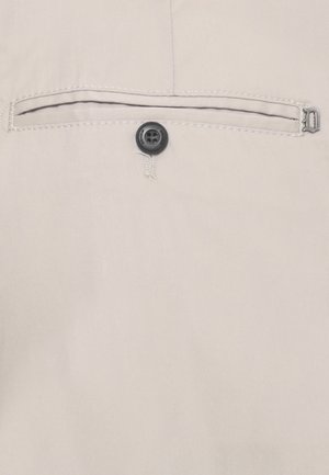 Tasca in tessuto beige con un singolo bottone nero e bordo cucito, caratterizzata da una piccola chiusura metallica sul lato destro.