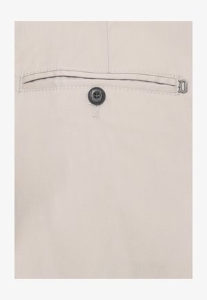 Tasca in tessuto beige con un singolo bottone nero e bordo cucito, caratterizzata da una piccola chiusura metallica sul lato destro.