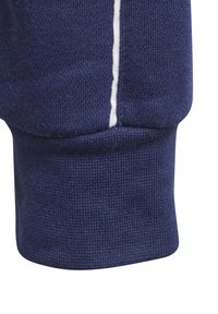 Manga de sudadera azul marino con puño acanalado, que presenta un detalle de costura blanca a lo largo de la costura y un acabado de tela texturizada.