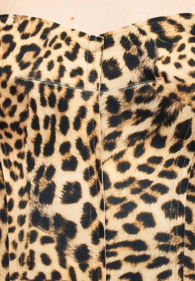 Ύφασμα με εκτύπωση λεοπάρδαλης που χαρακτηρίζεται από ομαλή υφή, με έντονες μαύρες κηλίδες σε ταμπα φόντο. Οι εκτεθειμένες ραφές τονίζουν το σχέδιο του ενδύματος.