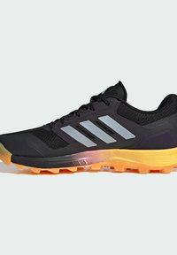 Černá sportovní bota vyrobená z prodyšných a syntetických materiálů, s metalickými stříbrnými pruhy, oranžovou podrážkou a texturovaným svrškem pro lepší úchop.
