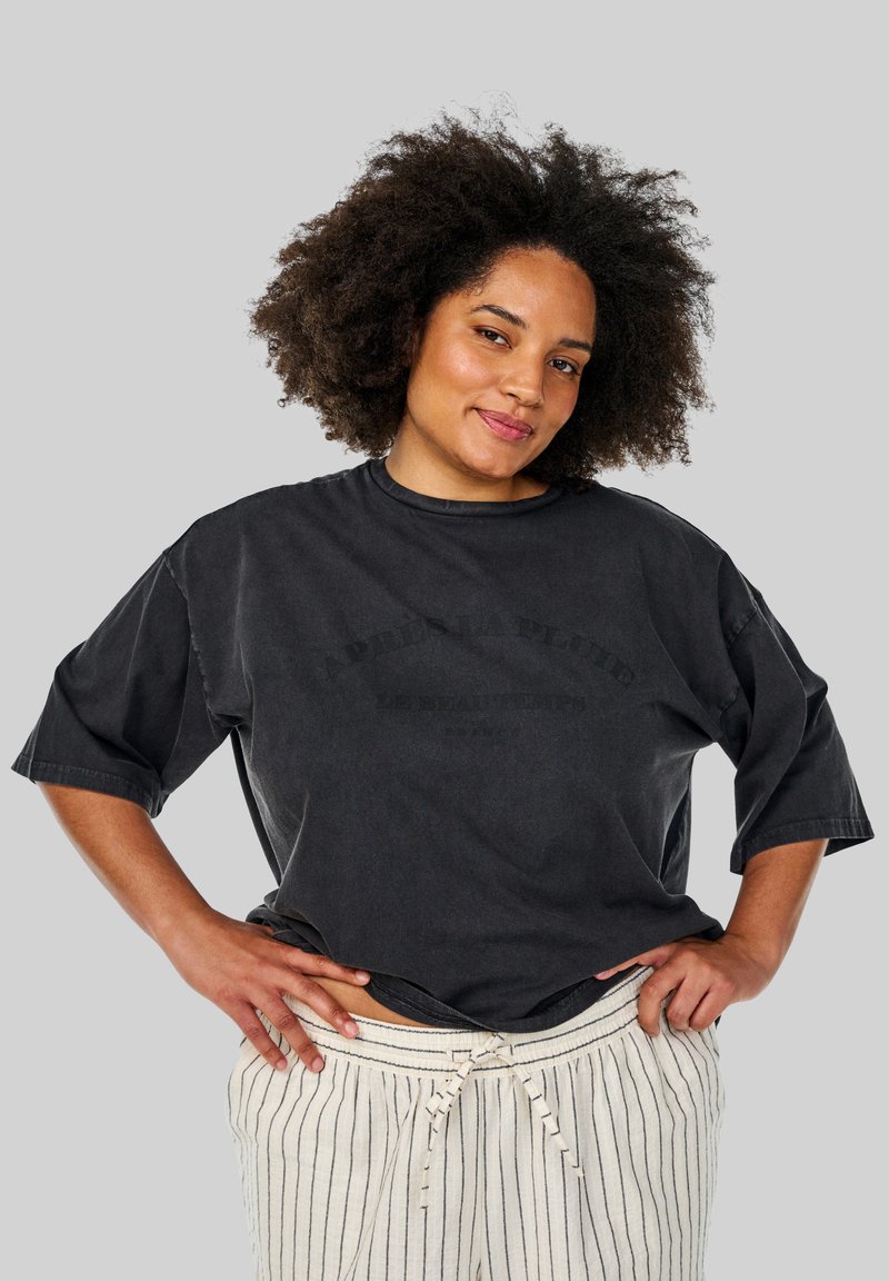 Sort oversized t-shirt med korte ærmer, der har et grafikprint i mørkegrå. Kombineret med cremefarvede stribede bukser med snøre.