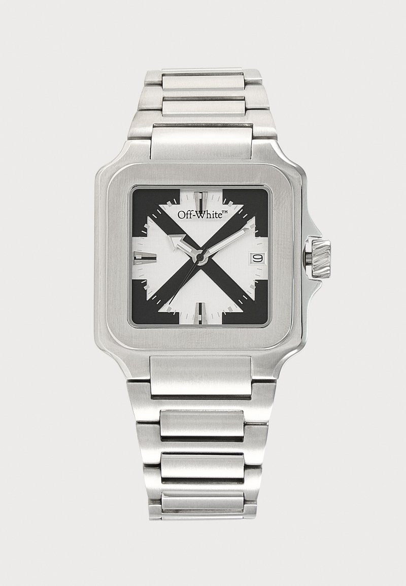 Montre carrée en métal argenté avec un motif de croix noir et blanc sur le cadran, aiguilles argentées, affichage de la date et bracelet à maillons.