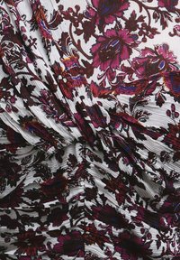 Top floral con base blanca, con patrones en burdeos y púrpura. La tela tiene un diseño texturizado plisado con detalles fruncidos.