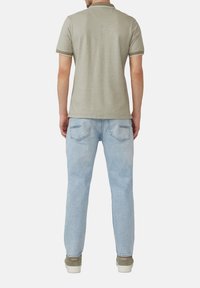 Szary polo z krótkimi rękawami, jasnoniebieskie dżinsy i szare trampki. Koszulka ma prosty kołnierzyk i biały wykończenie.