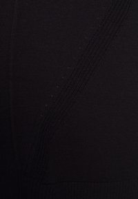 Tejido negro de punto con una textura suave, que presenta sutiles acentos acanalados y un patrón de costura diagonal para un detalle adicional.