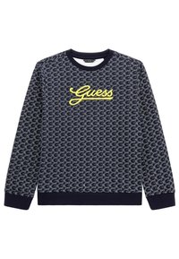 Niebieska bluza z logo Guess na piersi, w powtarzającym się jasnoszarym wzorze, z prążkowanym dekoltem i mankietami, wykonana z miękkiego materiału.