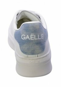 Sneaker bianco con un patch sul tallone in denim blu chiaro. Presenta il logo "GAËLLE" in bianco impresso sul tallone e una suola in gomma liscia.
