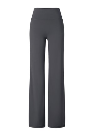 Femme aux cheveux tressés portant un t-shirt rose « FIRE + ICE », un pantalon évasé foncé, des baskets blanches épaisses, un bandeau noir et des lunettes de soleil futuristes.