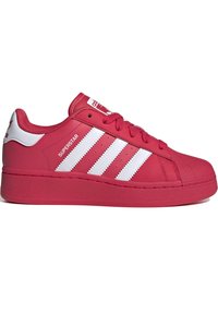 Röd Adidas Superstar-sneaker med vita ränder, strukturerad tåspets och "SUPERSTAR"-text på sidan, sedd från utsidan.