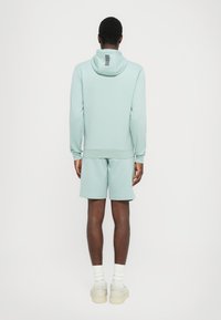 Mintgrønn hettegenser og shorts-sett i et mykt stoff. Hettegenseren har et lite stripete design på baksiden. Ledig snitt og komfortabel passform.