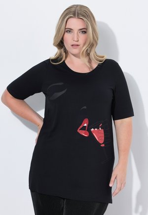 T-shirt noir à manches courtes avec un graphique de lèvres rouges et un verre à cocktail avec une paille, fabriqué en tissu doux et avec une coupe décontractée.