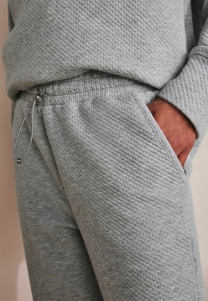 Helle graue Sweatpants aus strukturiertem Stoff, mit einem elastischen Taillenbund und einem Kordelzug sowie seitlichen Taschen.