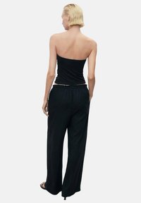 Black strapless top paired with loose black pants, featuring an elastic waistband. Smooth fabric with a relaxed fit.
