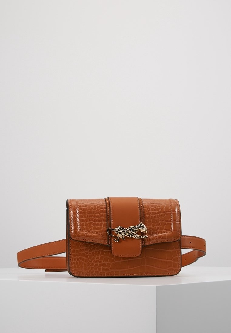 Brązowa torebka crossbody z imitacji skóry krokodyla, z klapką oraz dekoracyjnym detalem w leopardzi wzór. Posiada regulowany pasek i gładką teksturę.
