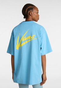 Vaaleansininen ylisuuri t-paita, jossa on lyhyet hihat ja keltainen "Vans"-logo selkäpuolella. Valmistettu pehmeästä puuvillakankaasta.
