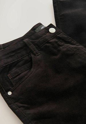 Mustad corduroy teksad, millel on tõmblukk ja hõbedane nööp, ees taskud ja silmapaistvad vertikaalsed riba muster kangas.