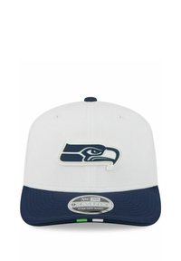 White and navy cap with a navy hawk logo on front and a "9SEVENTY Stretch-Snap" sticker on the navy brim.