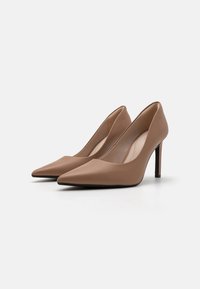 Béžové kožené lodičky na vysokom opätku s špicatou špičkou a štíhlym čiernym stiletto opätkom. Hladká textúra s minimalistickým dizajnom.