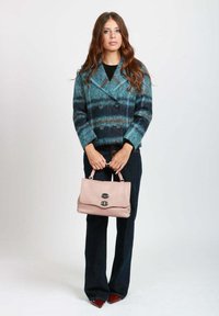 Cappotto doppiopetto in misto lana turchese e blu navy con righe orizzontali, abbinato a una borsa in pelle rosa pallido con chiusura a clasp.
