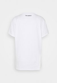 T-shirt bianca in cotone con collo a giro e maniche corte, caratterizzata da un logo nero "KARL LAGERFELD" sulla parte posteriore vicino al colletto.