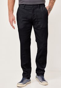 Black, textured trousers with a straight leg and side pockets, paired with blue low-top sneakers featuring white soles and laces.