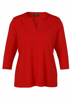 Haut rouge pour femme à manches trois-quarts avec encolure en V, fabriqué en tissu doux pour un porté décontracté et confortable.
