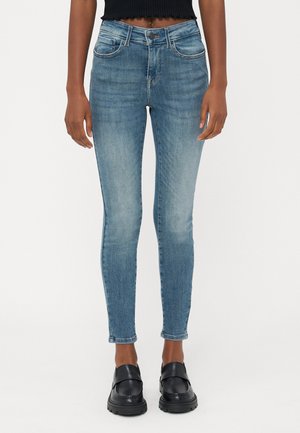 Slanke blauwe spijkerbroeken van denim, met een middelhoge taille, vijf zakken en een lichte vervaging. Gepaard met zwarte instappers.