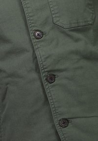 Olijfgroene blouse met knoopsluiting, voorzien van zwarte knopen en een enkele borstzak. Glad, lichtgewicht stof met een subtiele glans.