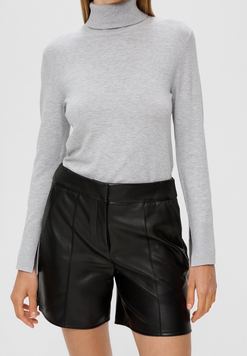 Helles graues Rollkragensweater mit langen Ärmeln, kombiniert mit hochgeschnittenen, schwarzen Leder-Shorts mit glatter Textur und Nahtdetails.