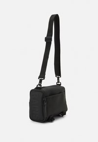 Borsa a spalla nera impermeabile realizzata in materiale liscio, forma rettangolare, dotata di cinturino regolabile, chiusura con zip e dettaglio logo stampato.