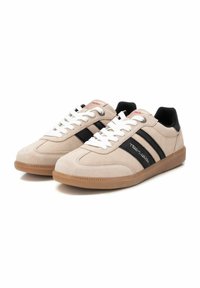 Sneaker in camoscio beige con strisce nere, lacci bianchi e suola in gomma. Presentano un logo sul lato e un collare imbottito per il comfort.