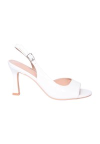 Sandal con tacco in vernice bianca, con punta aperta, design curvo ed elegante, e una sottile cinghia alla caviglia fissata con una fibbia in metallo.