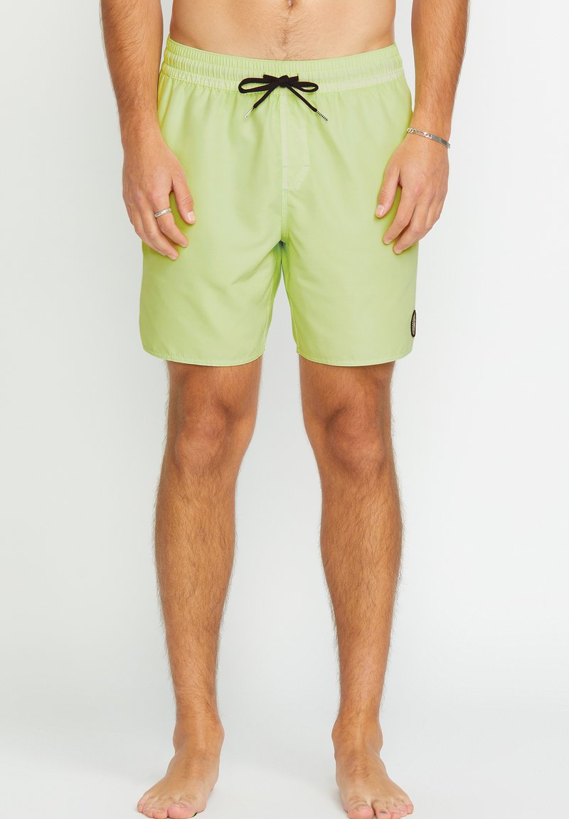 Costumi da bagno verde chiaro con cintura elastica, lacci neri e tasca laterale. Texture liscia con un'etichetta con logo sulla gamba sinistra.