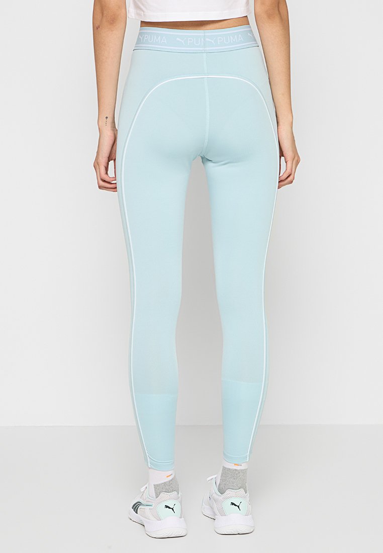 Leggings atletici blu chiaro con un alto elastico in vita, caratterizzati da cuciture laterali bianche e un leggero luccichio. Progettati per comfort e flessibilità.