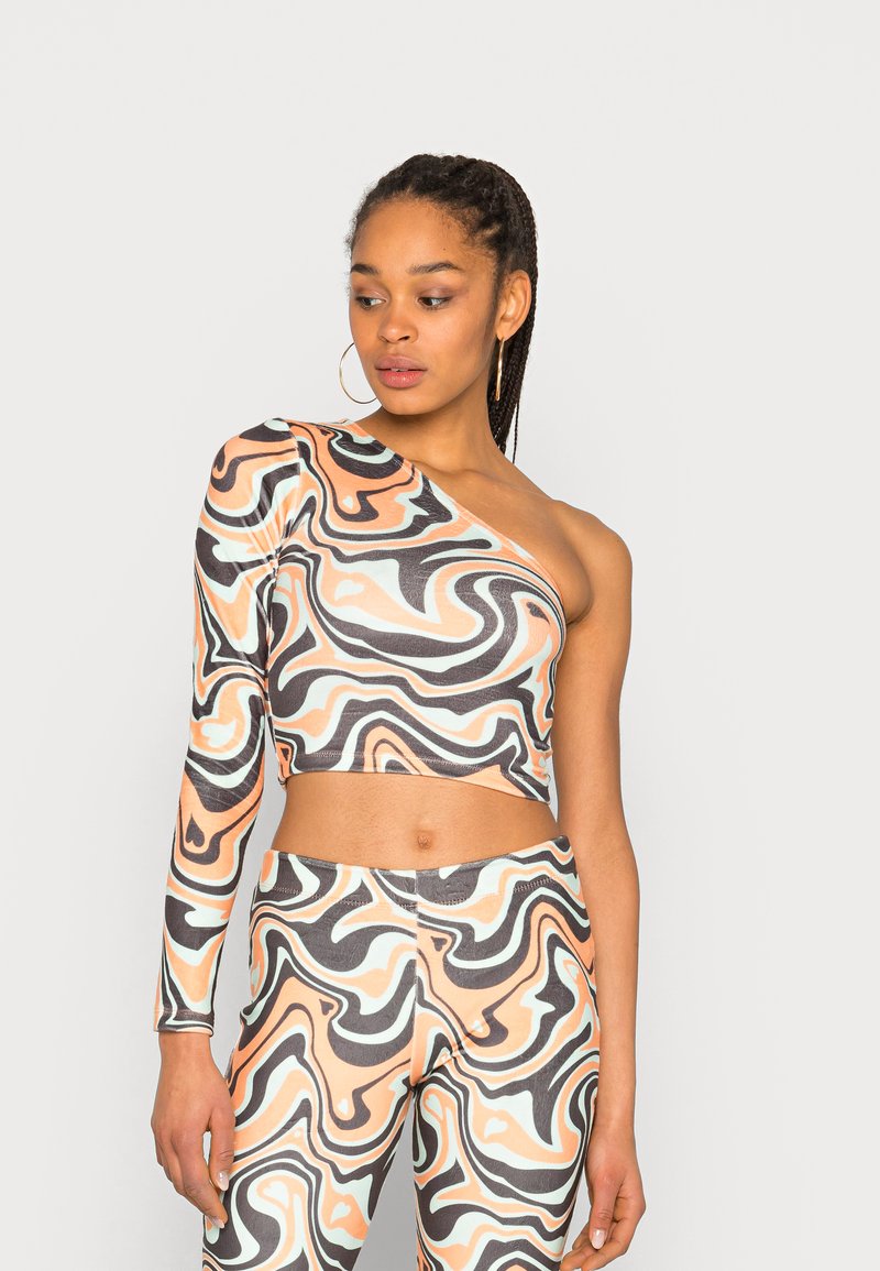 Top cropped de um ombro só com padrões ondulados abstratos em pêssego, preto e menta; ajustado com tecido elástico e leggings complementares.